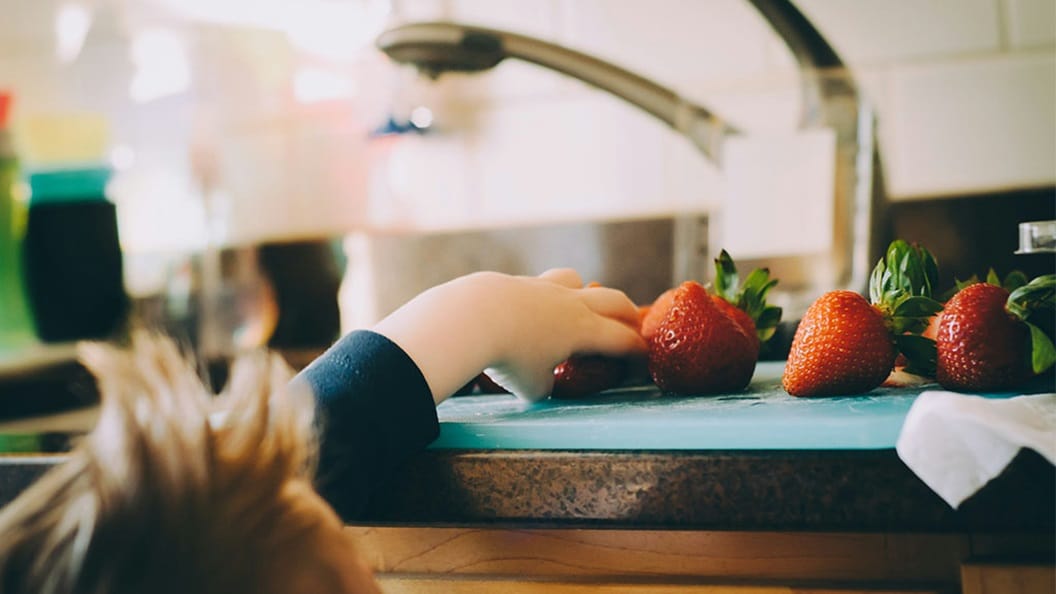 A child picking strawberries in a kitchen