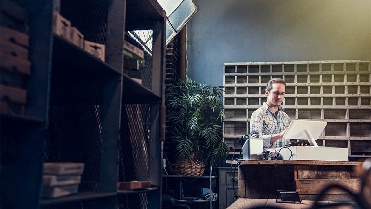 一位小企业主在货架前操作电脑。