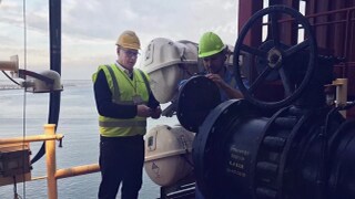 Two male in protective gear working on a ship