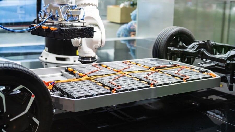 EV chassis with large flat lithium battery pack and orange power cables.