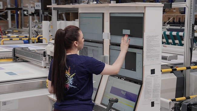 Person using multiple monitor screens in a manufacturing setup.
