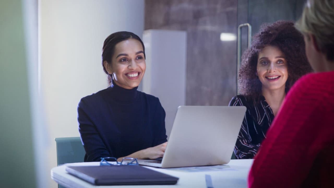 Two professionals smiling during a meeting.