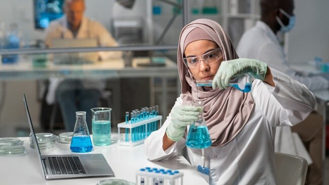 Scientist mixing blue liquid in lab flask.