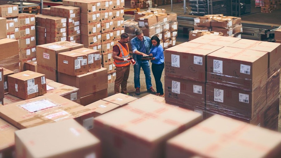 two male and a female working in a shipping warehouse