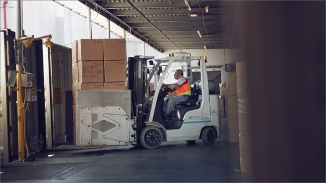Male sorting shipments using a forklift