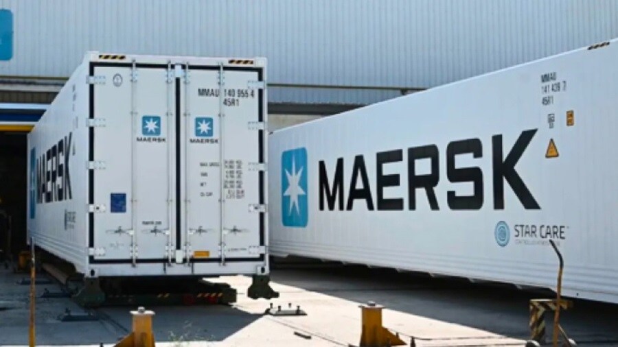 Two sizable white cargo containers featuring the "Maersk" logo, stacked in a shipping yard.