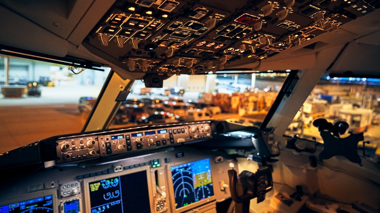 Nighttime view of an airplane cockpit, showcasing glowing dials and controls against a dark background.