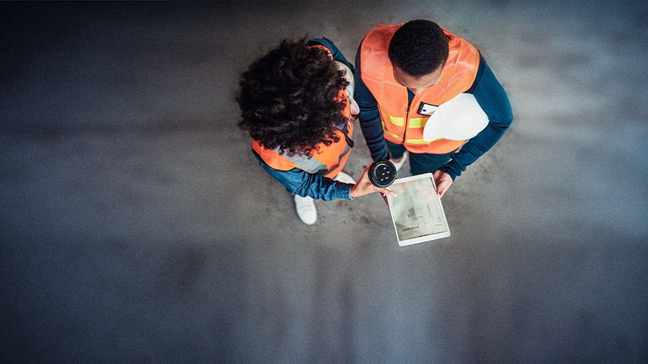 Two individuals in safety vests reviewing a document together, focused on the information presented on the paper.