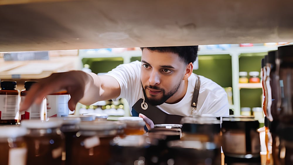 零售工人专注地整理货架上的罐子。