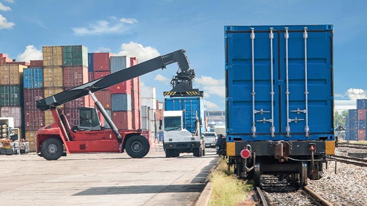 Intermodal logistics terminal with container loading onto truck and freight train using reach stacker.