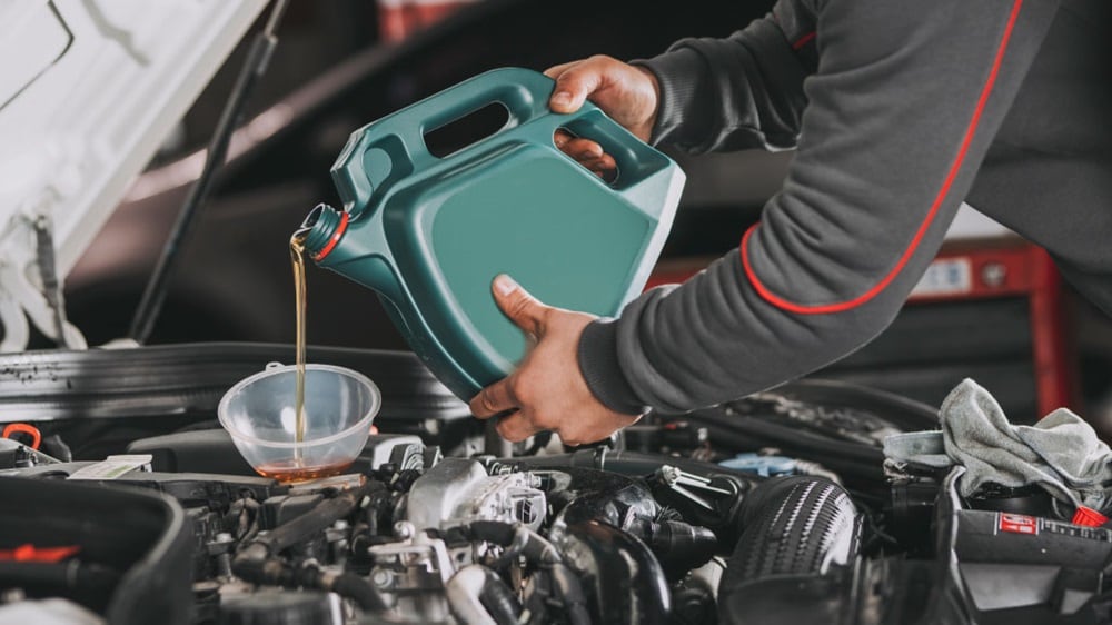 一双手将化学润滑剂倒入发动机